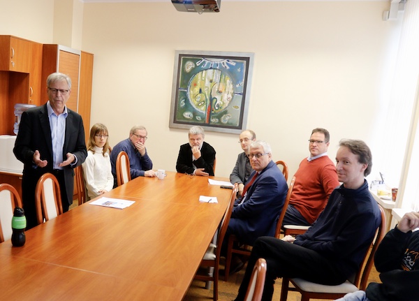 Prof. Józef Woźniak standing next to a table, with seven others listening